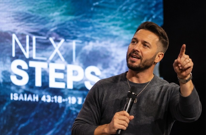 A pastor speaking on stage to a congregation
